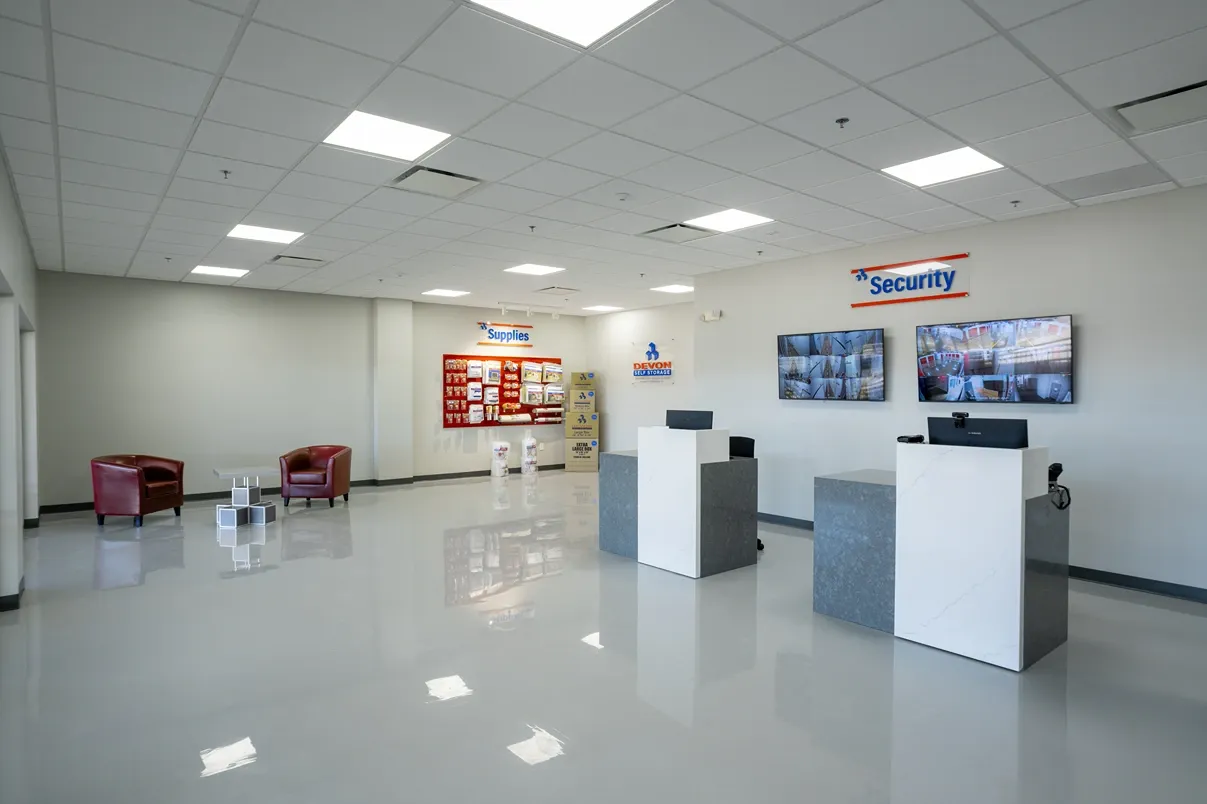 Self storage office lobby with customer service counters, seating area, and security monitors
